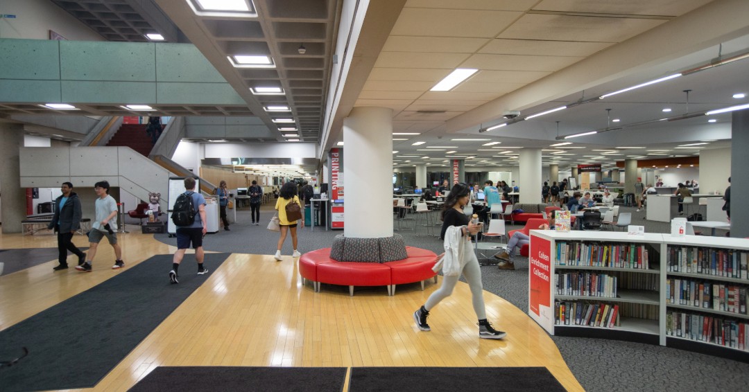 Inside photo of the entrance of Langsam Libriary with students walking around.